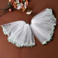 Dettaglio ravvicinato della mantellina in tulle bianco con bordo in pizzo di foglie verdi. - Bianco