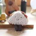Detail view of a cute plush sandwich pendant with embroidered smile and dangling legs. - Sandwich/Taco