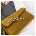 Chic mustard yellow suede crossbody bag with distinctive silver metal T-bar lock design. - Yellow