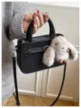Detail shot of a chic black handbag featuring a cute plush bunny charm, perfect for daily commuting. - With Pendant / Black