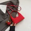 Red suede hobo shoulder bag with crossbody strap and cute pompom tassel charm variant. - With Pendant / Red
