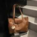 Brown retro PU leather tote bag, large capacity commuting handbag with flap and cute pendant style. - With Pendant / Brown
