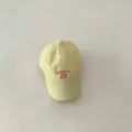Detailaufnahme der gelben Kinder-Baseballkappe mit rotem gestickten Textdesign vorne. - 48-52cm / Gelb