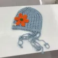 Nahaufnahme der handgehäkelten Lochstrickmütze, hellblau mit leuchtender orangefarbenen Blume. - 2-8 Jahre (Kopfumfang 49-53cm) / Hellblau