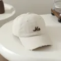 Nahaufnahme der beige Kinder Baseballkappe mit braunem bestickten Buchstaben Me am Rand. - 54cm Einstellbar Für 6-12 Jahre / Me Weiß