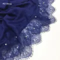 Close-up detail van de donkerblauwe sjaal met fijne kantrand en ingenaaide parels. - Donkerblauw