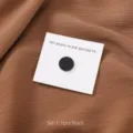 Gedetailleerd overzicht van de zwarte ronde hijab magneet op bruine stof, sterke sjaalclip. - 1 Stuk/Verpakking / Zwart