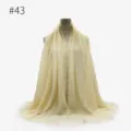 Dettaglio sciarpa frangiata stropicciata beige, texture morbida scialle copricapo, primo piano. - Stile 43