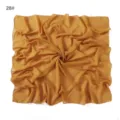 Detail view of a solid yellow chiffon square scarf showing its delicate crinkle texture. - Mint Dinosaur