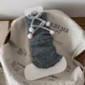 Grey knitted leg warmers with velvet bows and pom-poms, cozy winter fuzzy slouch socks. - Gray