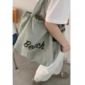Vista dettagliata della borsa tote casual in nylon con coulisse e stampa con lettere Beach. - Verde