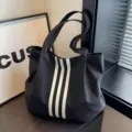 Dettaglio di una borsa shopper nera minimalista con strisce bianche e grande capacita. - Nero