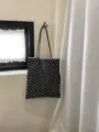 Vista dettagliata della classica borsa tote in tela a pois neri e bianchi appesa al muro. - Cinturino in pelle / pois bianchi e neri