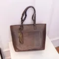 Dark brown PU leather tote bag with braided handles, stylish tassel, and front pocket design. - Dark Brown