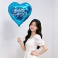 Blue heart foil balloon for birthday party, held by Asian model in white dress SKU - Bilingual Happy Birthday Model A / 5 Pieces/Pack / Blue