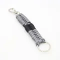 Detailed view of the woven paracord keychain, showing grey black cord texture and metal ring. - Gray + Black