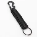 Black paracord keychain detail showing braided nylon structure and metal bottle opener hook. - Black