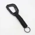 Close-up detail of black paracord keychain with plastic carabiner and metal ring. - Black