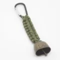 Detailed close-up view of the outdoor camping anti-bear bell paracord keychain attachment. - Army Green