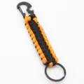 Detail view of black and orange paracord keychain with carabiner and integrated bottle opener. - Orange And Black