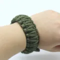 Detailed view of the army green tactical paracord survival bracelet, showing exquisite weaving. - Army Green