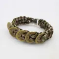 Detailed close-up of the woven paracord bracelet featuring antique copper coin charms. - Army Green Camo