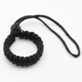 Black woven paracord camera wrist strap detail closeup, durable nylon survival lanyard cord. - Black