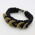 Detailed view of the black paracord survival bracelet decorated with vintage copper coins. - Black