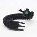Black paracord survival bracelet with compass, whistle, scraper, and fire starter. - Black