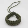 Detailed close-up view of a dark green woven paracord camera wrist strap and hand lanyard. - Army Green