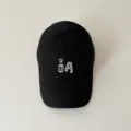 Nahaufnahme Detail einer trendigen schwarzen Baumwoll Baseballcap mit weißer Stickerei, vorne. - Kinder 50-54cm / Schwarz