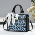 Borsa a mano leopardata blu con elegante foulard a fiocco, dettagli in vernice e tracolla. - Blu