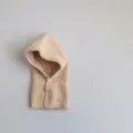 Detailed view of a cozy baby knit balaclava in beige, featuring fine ribbed texture and buttons. - Off-White