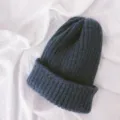 Close-up detail of a soft knitted beanie cap, solid navy blue color, ribbed winter warm hat. - One Size / Blue Gray