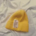 Nahaufnahme der gelben Strickmütze Textur, weicher Wollstoff mit einem Retro-Etikett. - Kinder Gelb