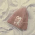 Nahaufnahme der rosa Strickmuetze mitweissem Textaufnaeher fuer warme Kinder Freizeitmuetze - Kinder Rosa