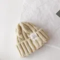 Details of the children cable knit beanie in beige with stylish cloth label for winter warm wear. - 50-60cm / Beige