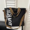Trendy large capacity canvas tote bag with brown shoulder straps and chic letter print. - Black