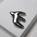 Broche hirondelle abstraite exquise vue détail, finition métallique lisse, élégant accessoire. - Broche