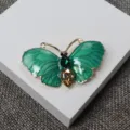Gros plan détaillé de la broche papillon en émail vert avec des strass en forme de larme. - Vert