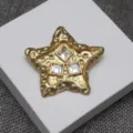 Gros plan de bijoux d'étoile texturée en lave vintage avec trois strass carrés brillants. - Broche