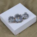 Vue détaillée d'une pince à cheveux fleur de perle émaillée vintage aux pétales gris. - Gris clair