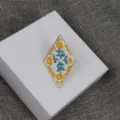 Vue détaillée de la broche émaillée en forme de losange avec de superbes motifs floraux. - Style 3