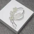 Gros plan détaillé d'une broche fleur en perles et strass argenté, accessoire de costume chic. - Argent