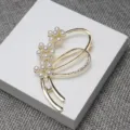 Gros plan d'une broche dorée en perles et strass avec motif floral pour pulls élégants. - Or
