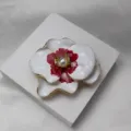 Gros plan détaillé de la broche pendentif fleur de phalaenopsis en émail blanc et rouge. - Broche