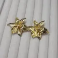 Gros plan de bijoux floraux en métal doré exquis, texture élégante et finition brillante attrayante. - Boucles d'oreilles clous