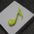 Close-up detail of a bright green enamel musical note brooch, elegant fashion accessory. - Bright Green