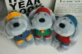 Close-up detail of cute grey plush puppy toy with colorful outfits and headbands, soft texture. - Athletic Champion