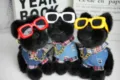 Simpatico cucciolo di peluche nero con occhiali da sole colorati e camicia di jeans dettaglio. - Stile di Strada alla Moda
